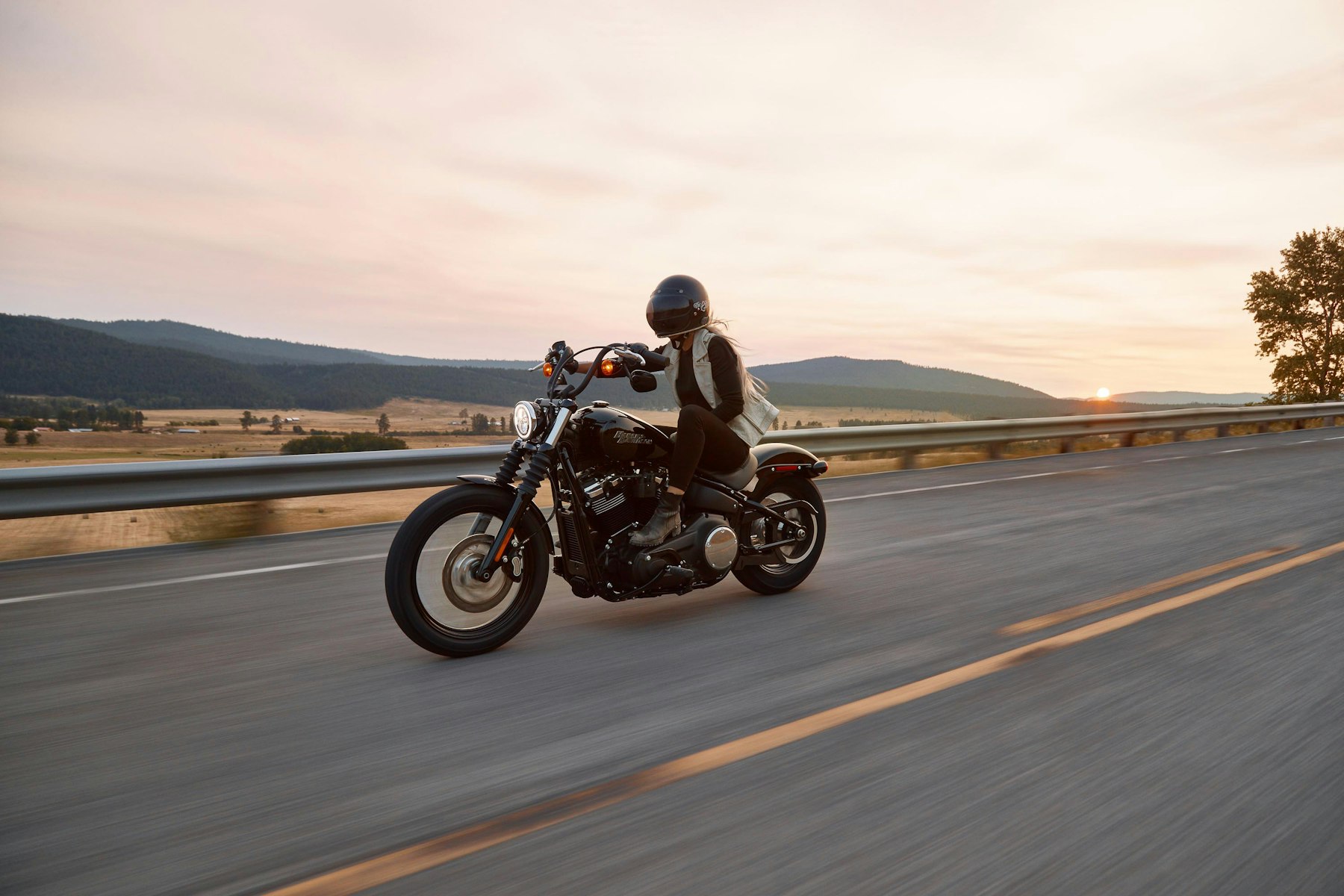 Motociclista en una ruta con una moto custom al atardecer